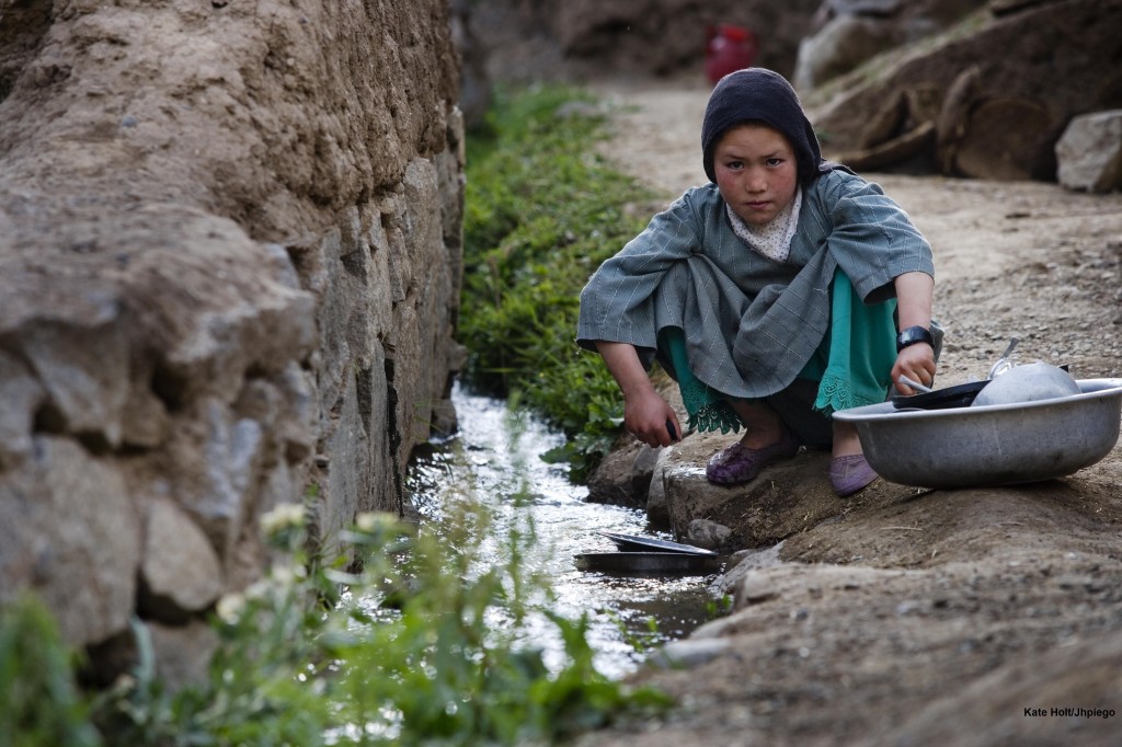 A young girl washes her families pots in a stream outside of the village of Katasank, Bamyan, Afghanistan.
