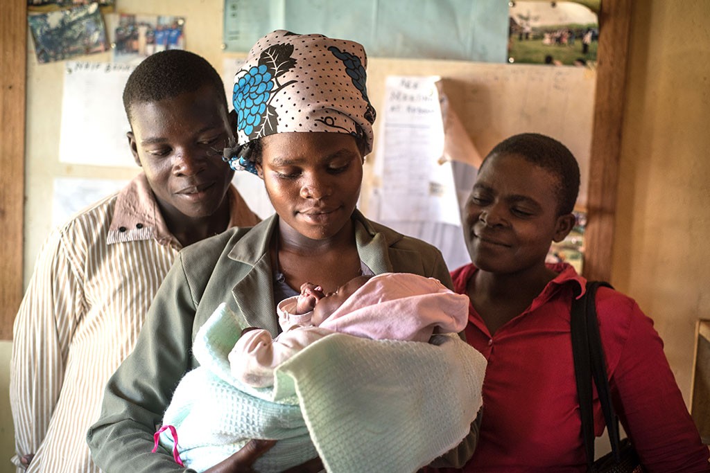 Sarah Naisambu and her husband, Ishmael, hold their daughter, Tabitha, as Joyce Njunukha looks on.