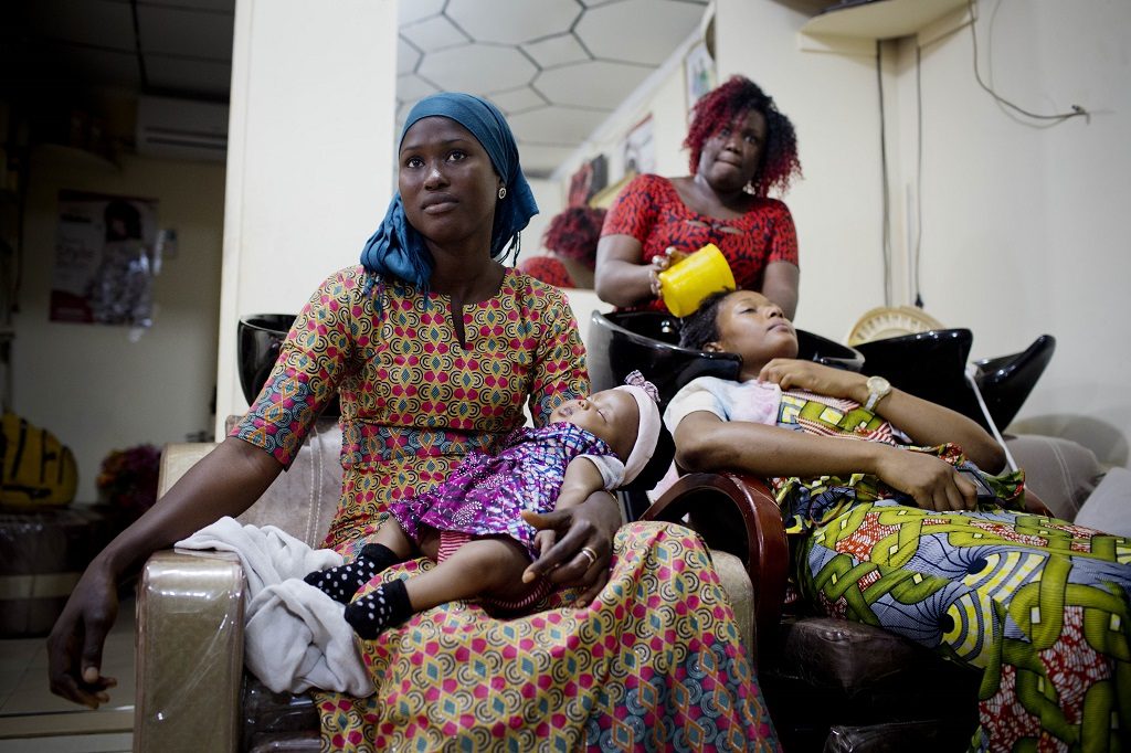 Woman holds her child at a hair salon in Guinea