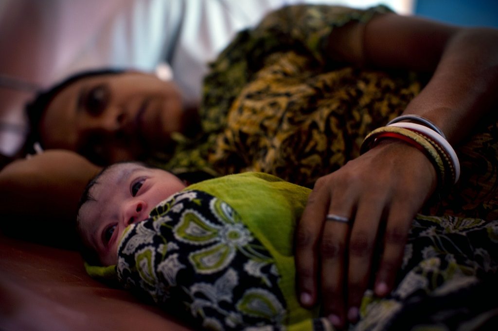 Mother and newborn resting at a health facility in India.