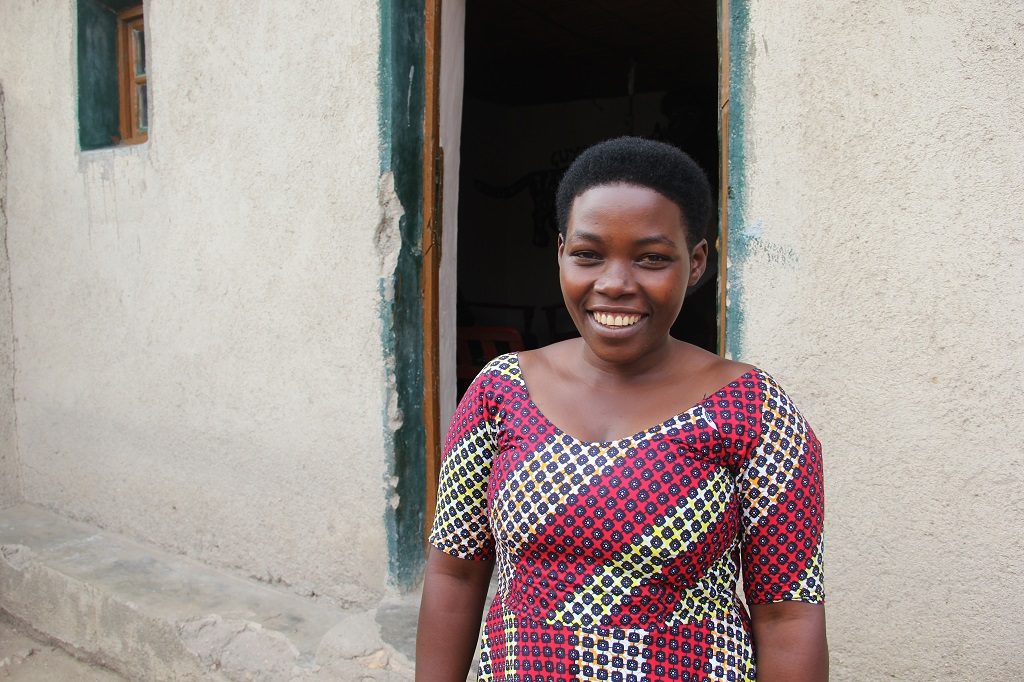 Claudine smiling outside her home in Rwanda