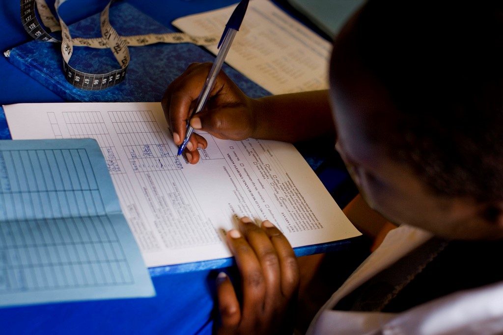 A midwife records medical data for an expectant mother in the maternity unit of Nemba Hospital, Rwanda.