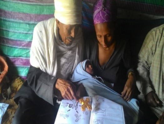 Kes Melakeselam, an Orthodox priest, using a family health guide to educate Abeba Mesele, who recently gave birth to a baby boy.