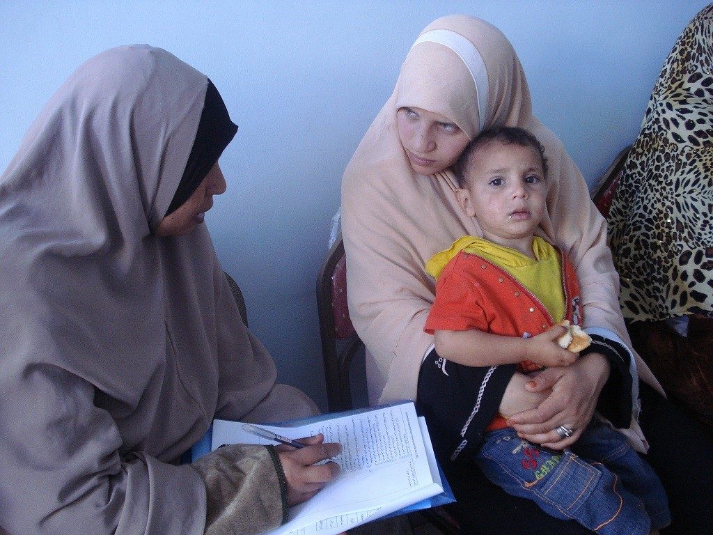Egyptian mother holding child and talking to health worker